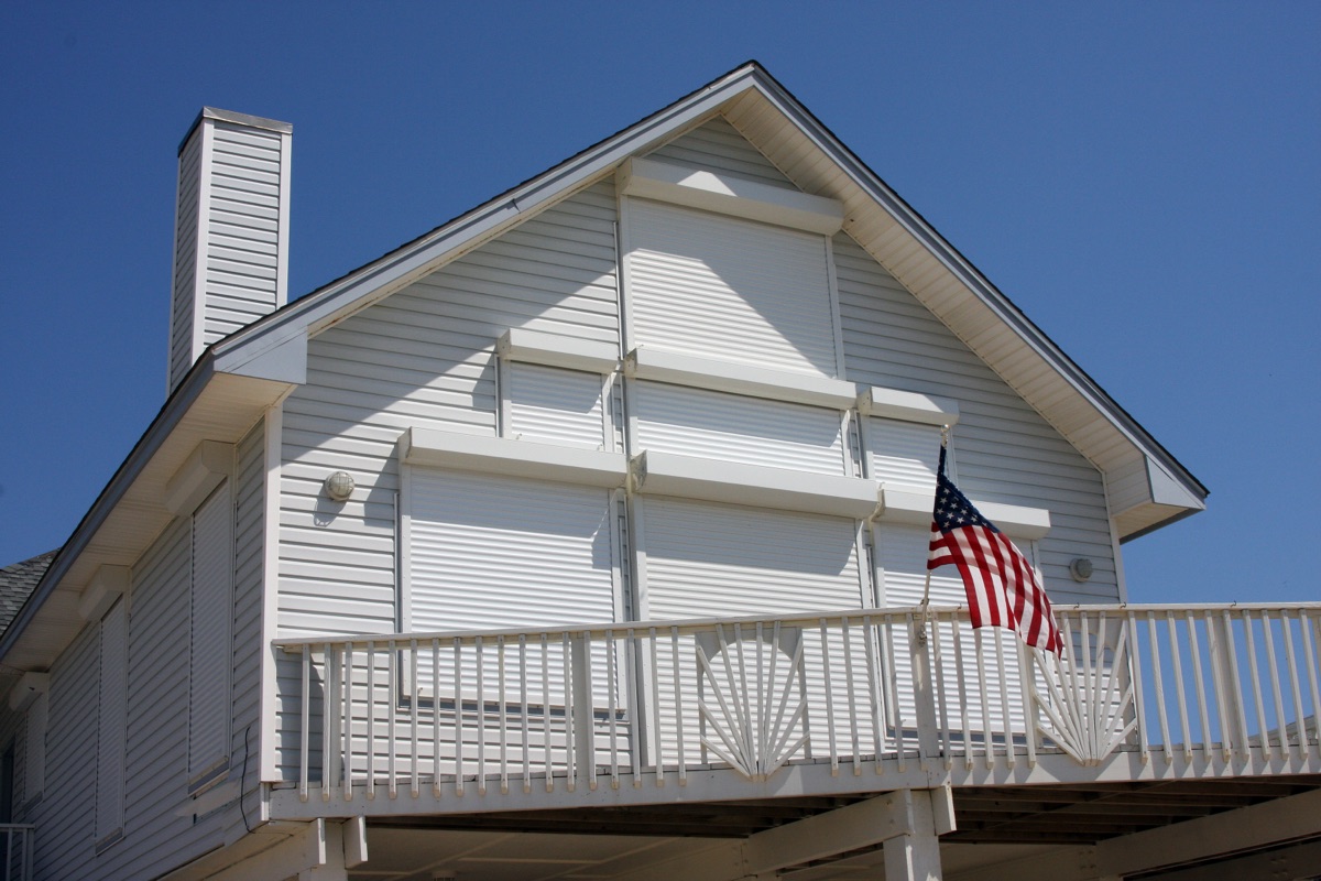 Storm shutters installed over the windows and doors of a coastal home ahead of a hurricane