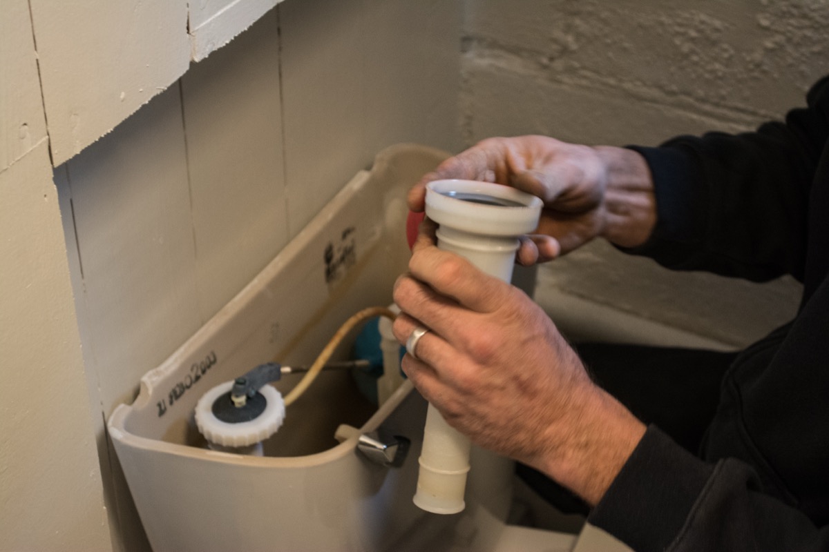 Close-up of a toilet water supply shutoff valve being turned