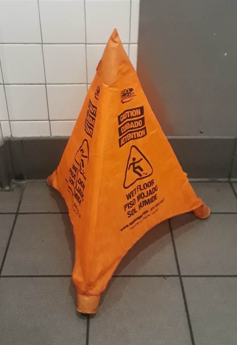 Wet floor caution sign set up in a bathroom after cleanup begins