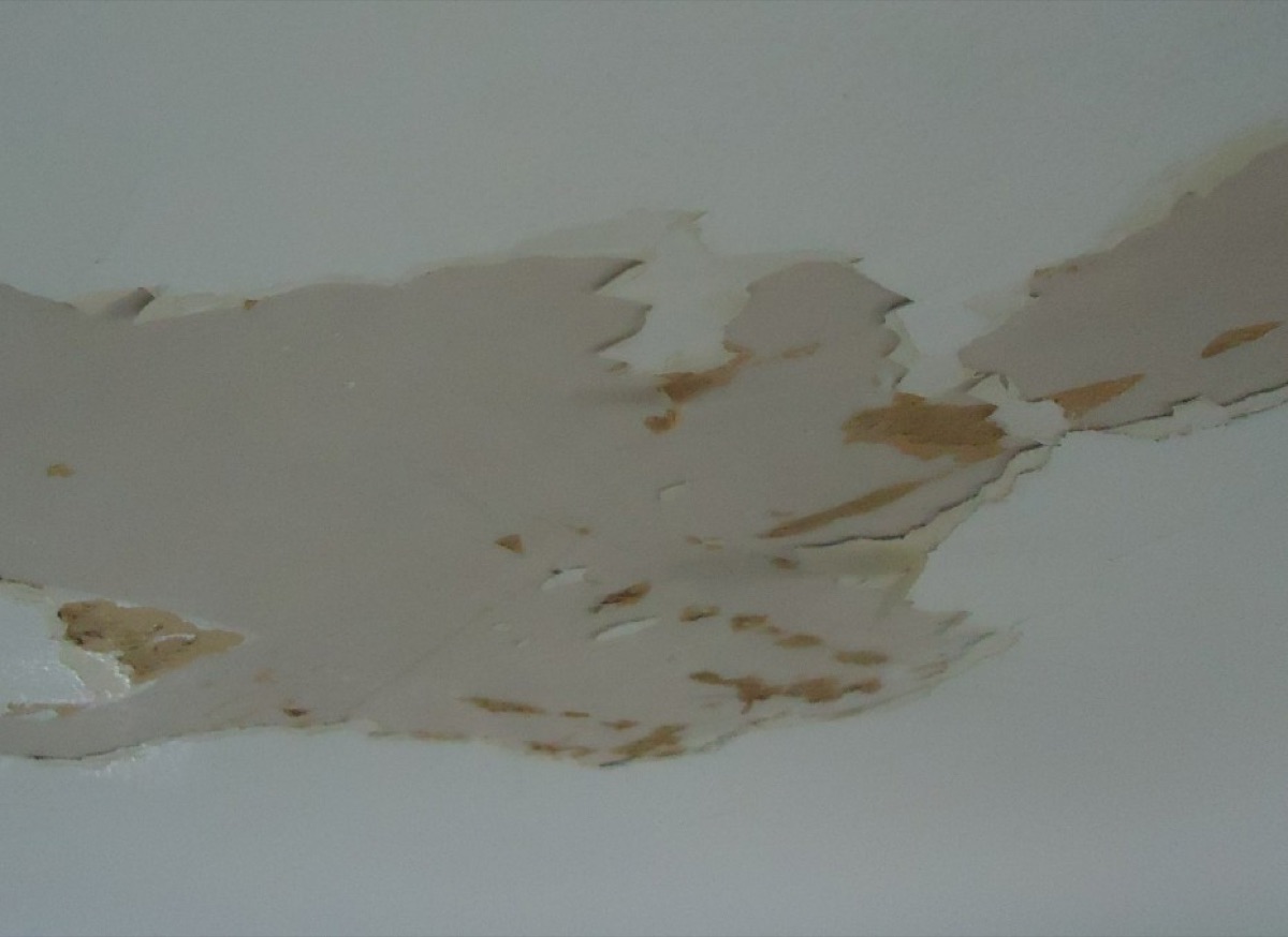 Peeling paint and a sagging drywall ceiling section damaged by a slow water leak